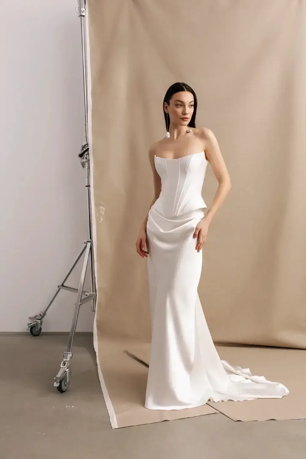A woman in a strapless white gown poses against a neutral backdrop.