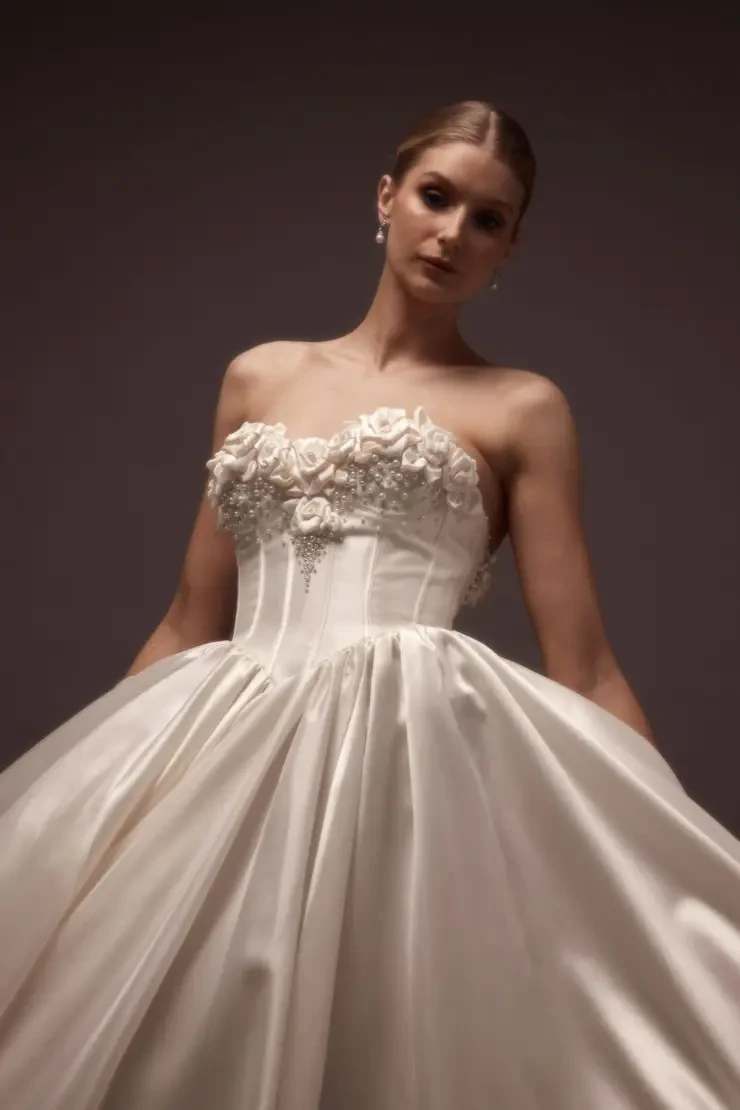 A woman wearing an elegant strapless wedding gown with floral embellishments.